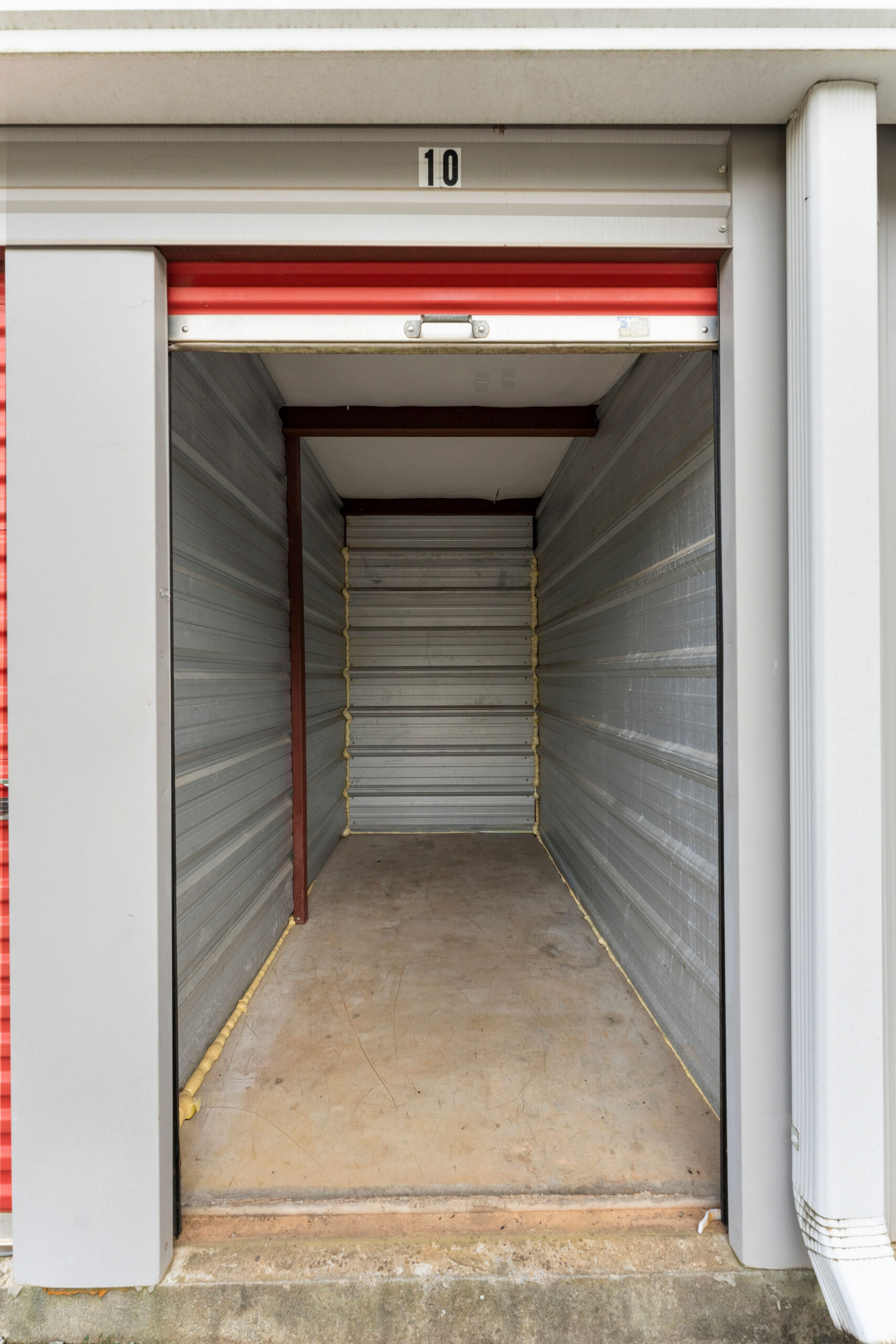 Open drive-up storage unit number 10 with a red roll-up door