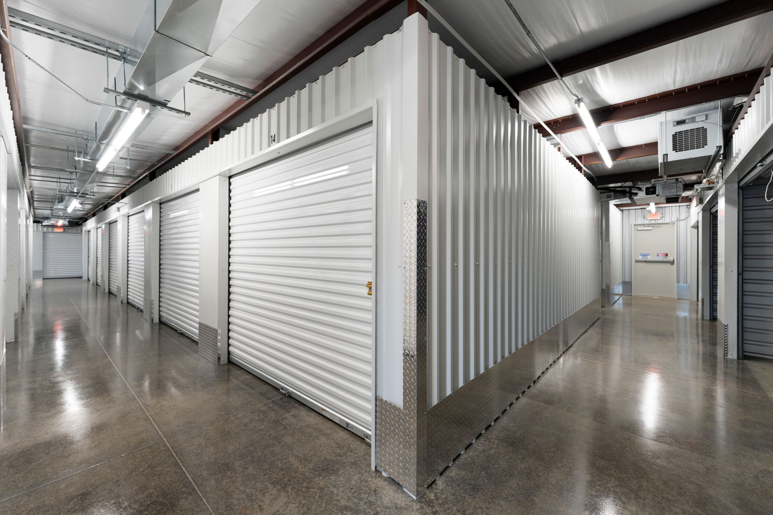 Indoor storage hallways meeting at a corner with white unit doors